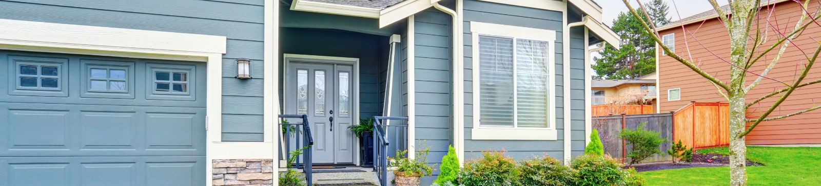 Front view of a Grayslake home featuring a gray garage door, double front doors, and well-maintained landscaping.