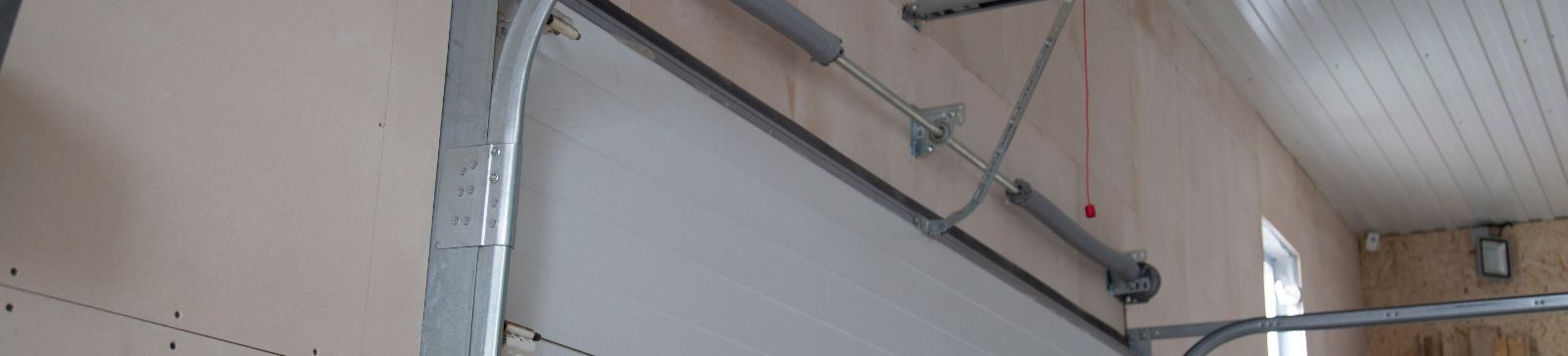 High angle view of a sectional garage door, tracks, and opener system professionally installed in a well-lit Grayslake IL garage