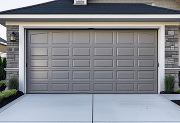 Modern gray garage door freshly installed on a stylish Grayslake, IL residence with stone accents.