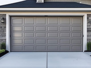 Modern gray garage door freshly installed on a stylish Grayslake, IL residence with stone accents.